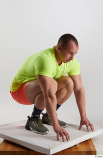 Joel  1 dressed green sneakers kneeling orange shorts sports…